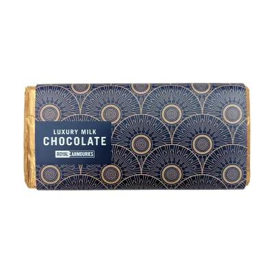 Luxury milk chocolate bar wrapped in gold foil, featuring dark blue packaging with gold circular motifs and Royal Armouries branding