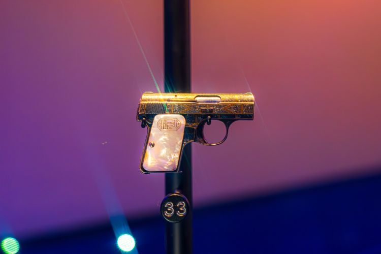 Gold Baby Browning Pistol with white marble effect handle and intricate decorative engraving on the barrel